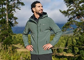 Collection of men's mountain equipment including technical jackets, pants, and base layers arranged for gear review